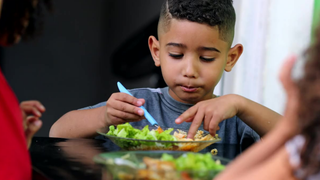 Young boy sits at a table eating a salad with a fork.

Caring Gift of Food