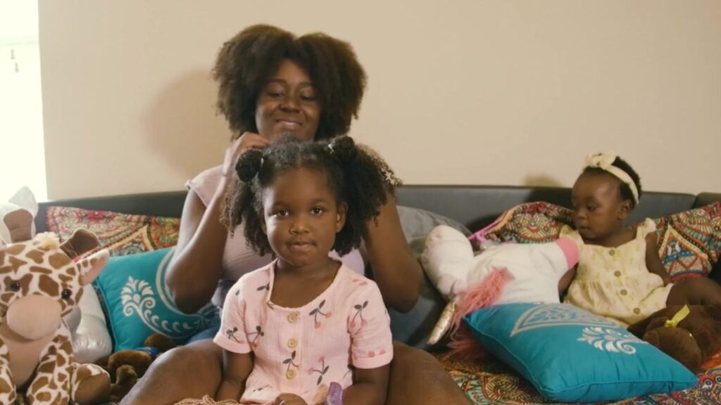 A smiling mother fixes her daughters hair on a couch while her younger daughter plays next to them.

Caring Gift of Shelter